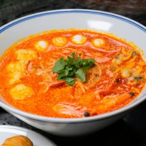 Delicious Thai Tom Yum soup with seafood and vegetables, garnished with cilantro in a ceramic bowl.