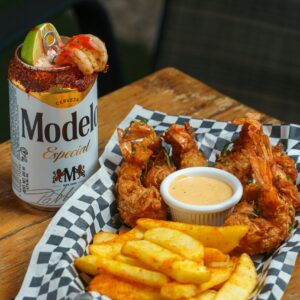 A delicious combo of crispy fried shrimp and fries paired with a Modelo beer.