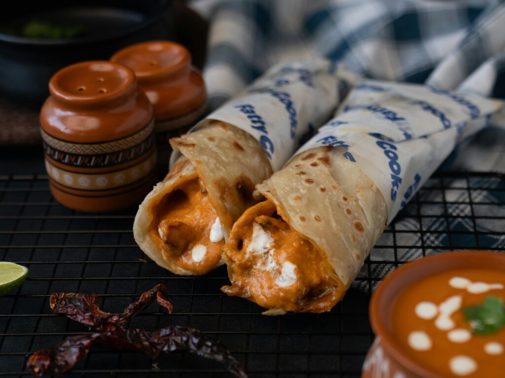 Close-up of spicy tandoori chicken rolls with sauce and spices, perfect for food enthusiasts.