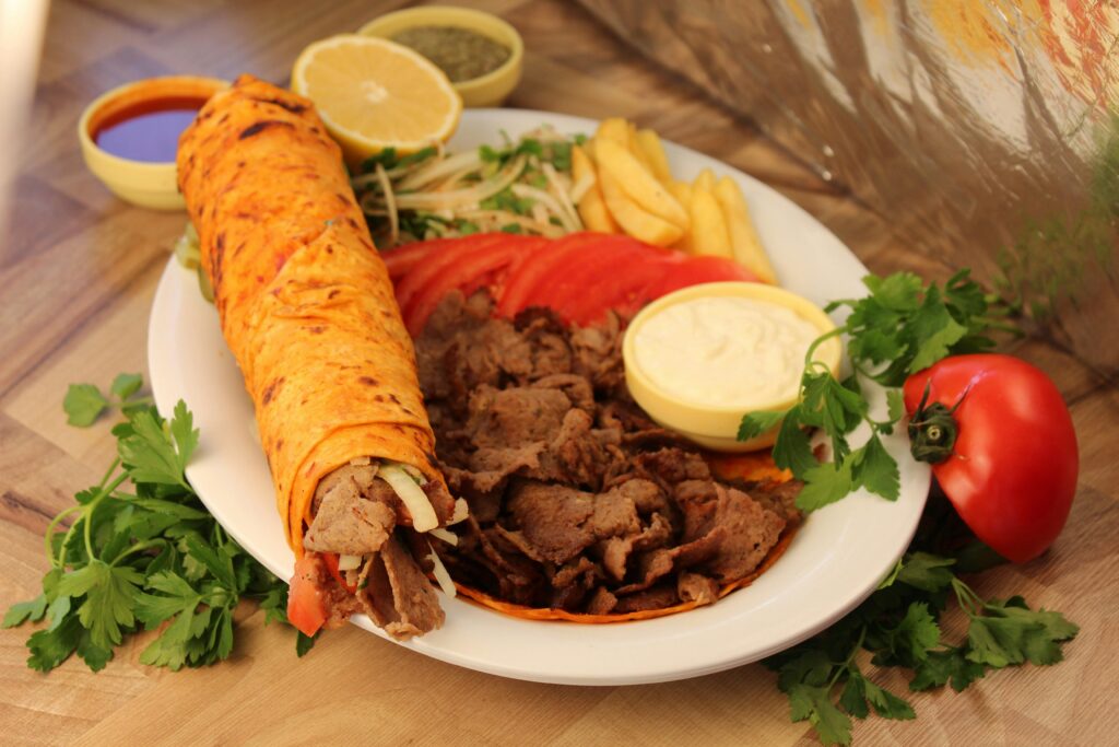Appetizing Middle Eastern shawarma with lavash bread, sauces, and fresh vegetables on a plate.